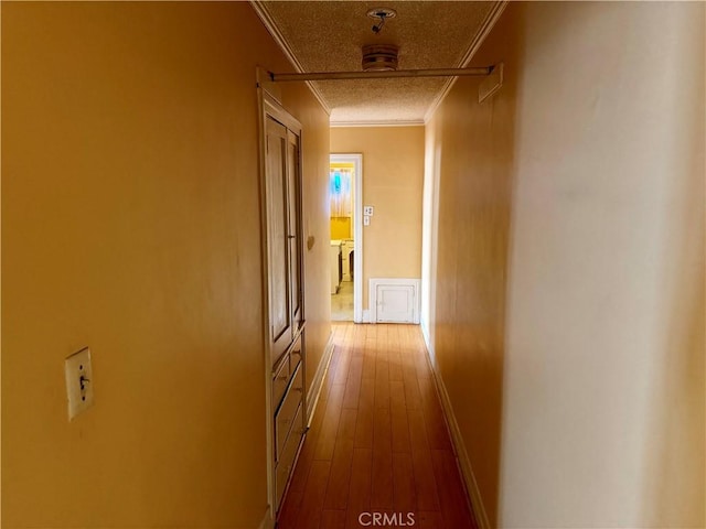 corridor featuring wood-type flooring, crown molding, and a textured ceiling