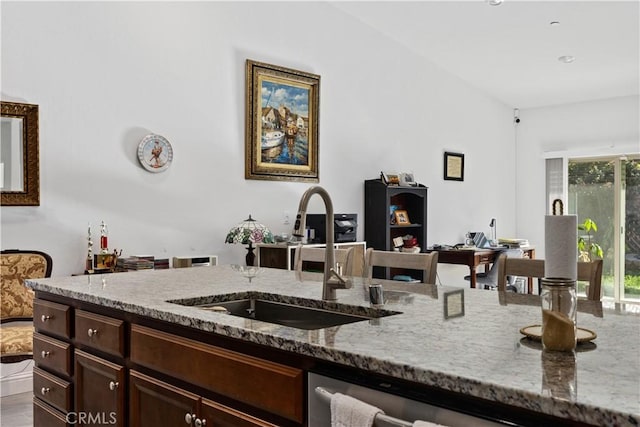 kitchen featuring sink, dishwasher, dark brown cabinets, and light stone countertops