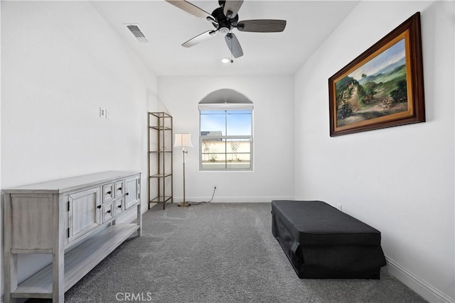 living area with ceiling fan and dark carpet