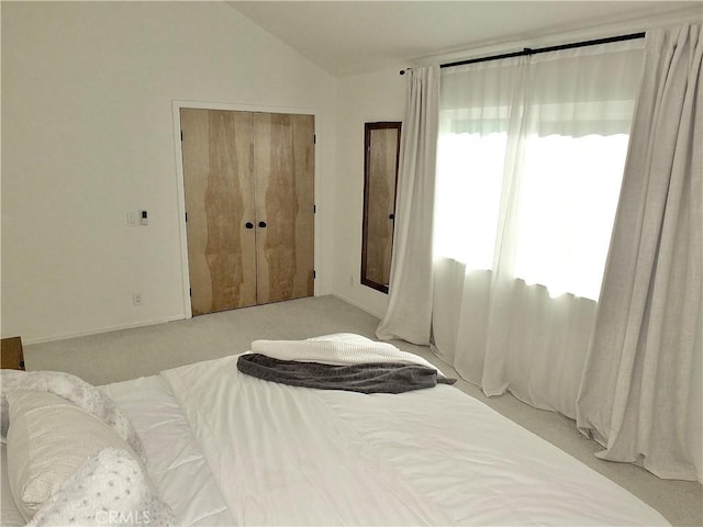 bedroom with a closet, lofted ceiling, and light colored carpet