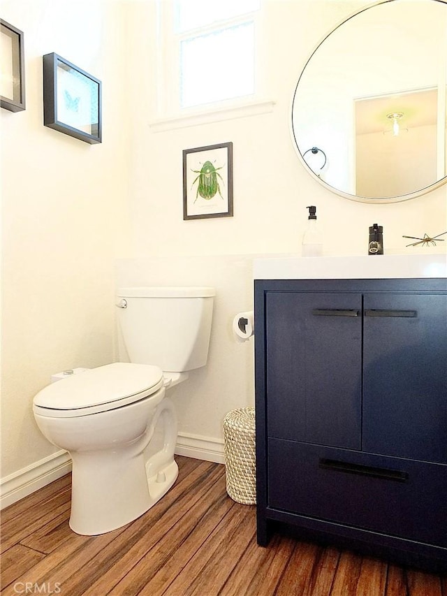 bathroom with vanity, toilet, wood finished floors, and baseboards