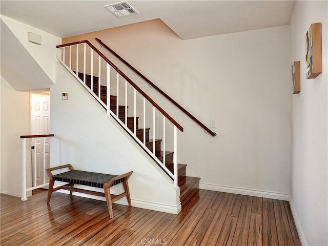 staircase with visible vents, wood-type flooring, and baseboards