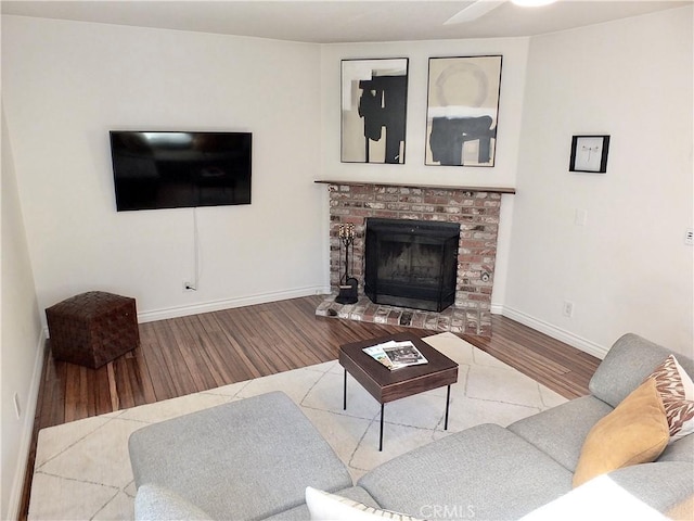 living area featuring a brick fireplace, wood finished floors, and baseboards