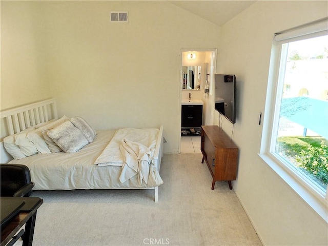 bedroom with vaulted ceiling, connected bathroom, visible vents, and light carpet