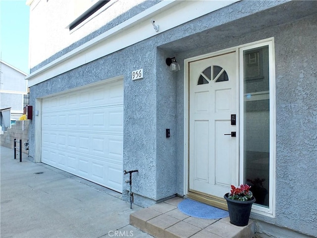 entrance to property with a garage and stucco siding