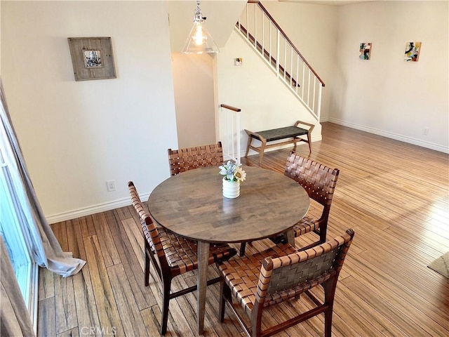 dining space featuring hardwood / wood-style floors, stairway, and baseboards