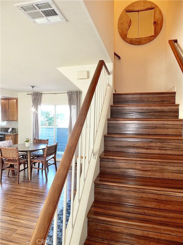 stairs with visible vents and wood finished floors