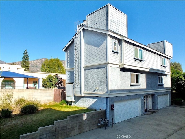 view of side of home with stucco siding, concrete driveway, and an attached garage