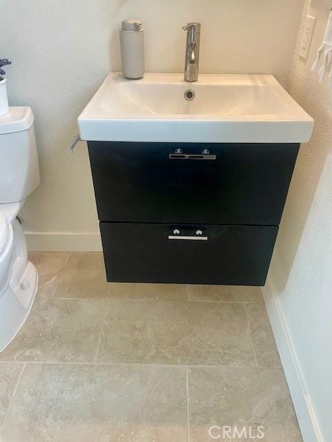 bathroom with baseboards, toilet, and vanity