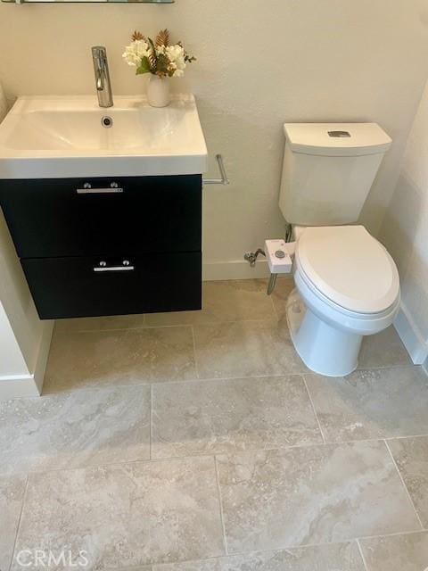 bathroom featuring baseboards, toilet, and vanity