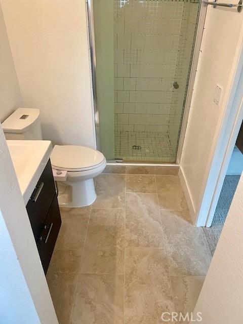 bathroom featuring a shower stall, toilet, vanity, and baseboards