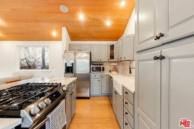 kitchen featuring appliances with stainless steel finishes, gray cabinetry, light hardwood / wood-style floors, and wooden ceiling