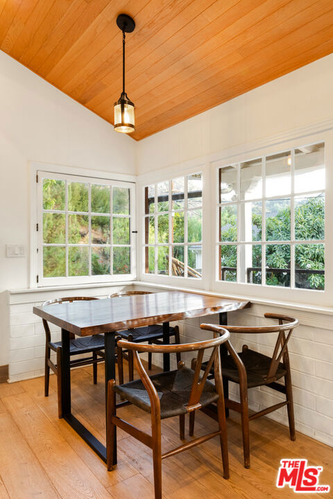 dining room with vaulted ceiling, wooden ceiling, light hardwood / wood-style floors, and plenty of natural light