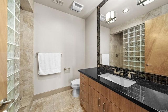 bathroom with walk in shower, vanity, tasteful backsplash, and toilet