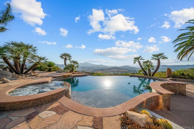 view of pool featuring an in ground hot tub and a water and mountain view