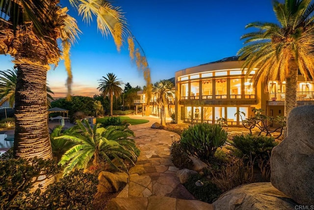 back house at dusk featuring a balcony and a patio