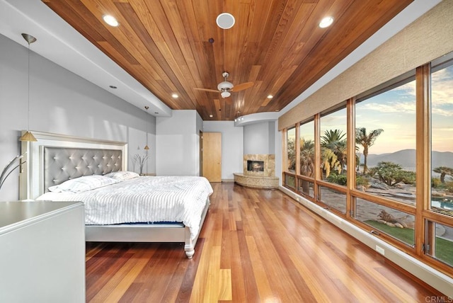 bedroom with wood ceiling, a fireplace, and hardwood / wood-style flooring