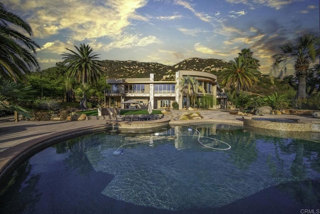 pool at dusk with an in ground hot tub