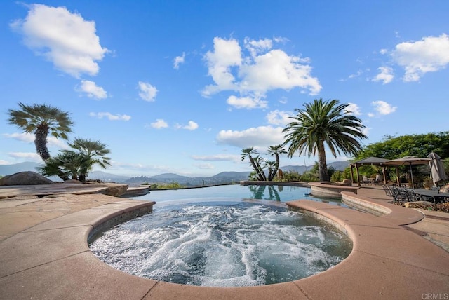 view of pool with a gazebo, a water and mountain view, a patio area, and an in ground hot tub