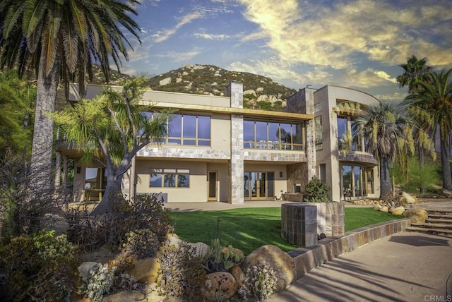 back of house featuring a lawn and a mountain view