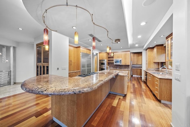 kitchen with built in appliances, light stone countertops, pendant lighting, and tasteful backsplash