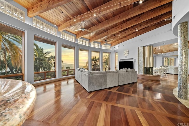 living room featuring ceiling fan, wood ceiling, a towering ceiling, and beam ceiling