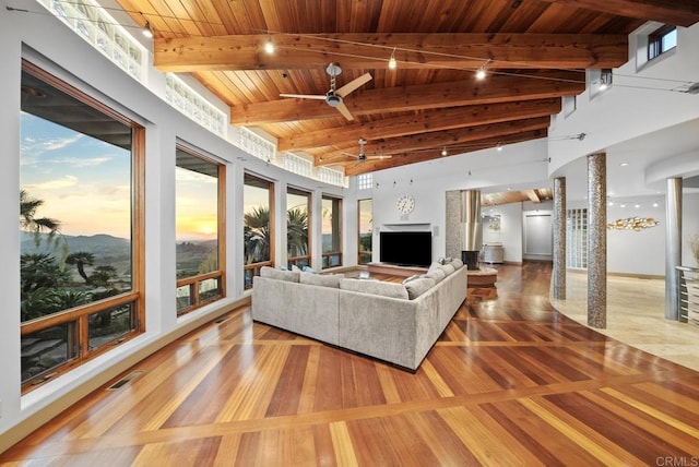 living room with a healthy amount of sunlight, a high ceiling, wood ceiling, beam ceiling, and ceiling fan