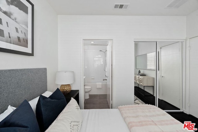 bedroom featuring dark tile patterned floors, a closet, and connected bathroom