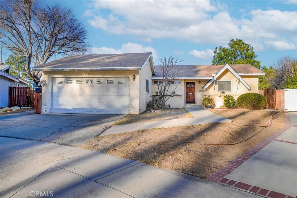 ranch-style home featuring a gate, fence, and stucco siding