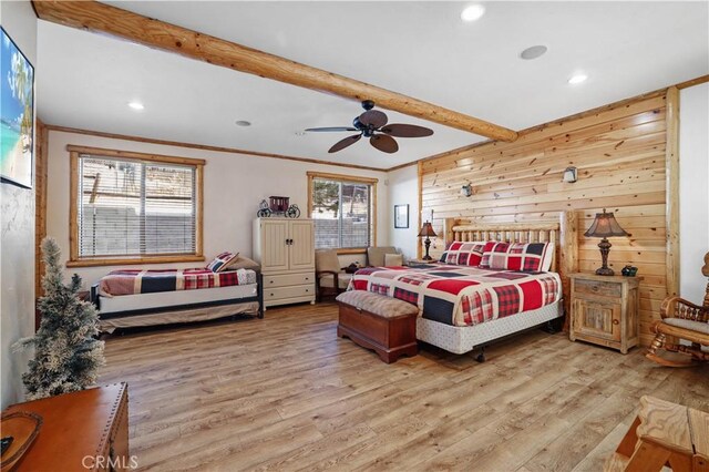 bedroom with ceiling fan, wooden walls, beamed ceiling, and multiple windows