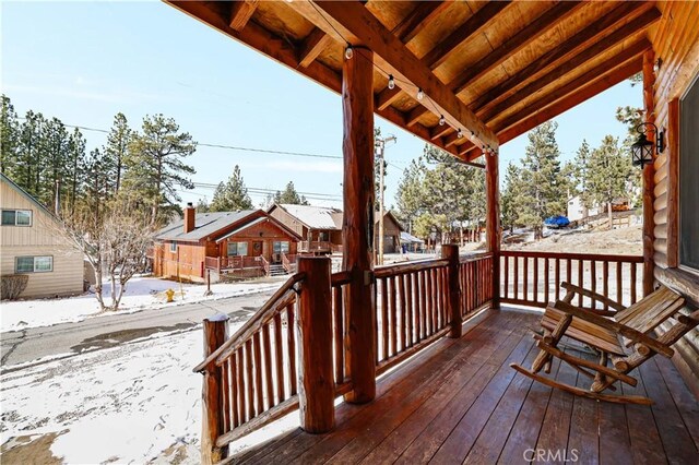 snow covered deck featuring covered porch