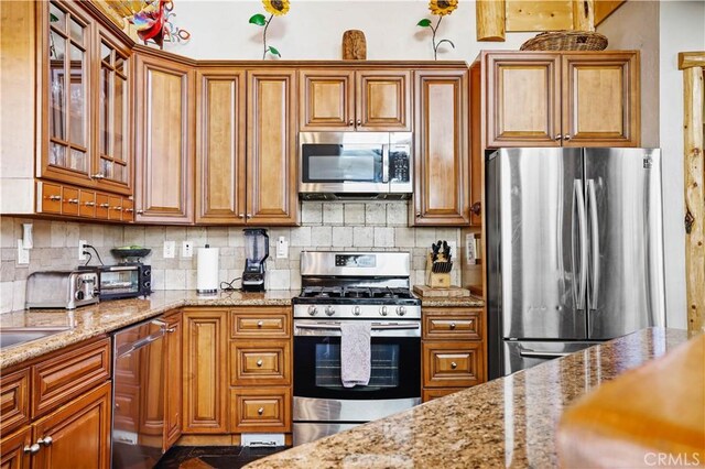 kitchen with stainless steel appliances, light stone countertops, and backsplash