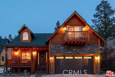 log home featuring covered porch, a balcony, and a garage