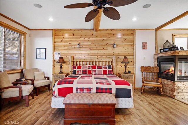 bedroom featuring ceiling fan, ornamental molding, wood walls, and wood-type flooring