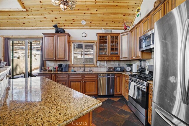 kitchen featuring stainless steel appliances, sink, lofted ceiling, tasteful backsplash, and light stone countertops