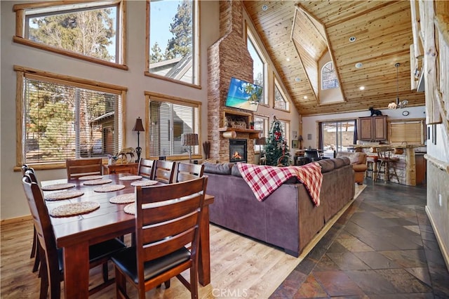 living room featuring a high ceiling, wood ceiling, and a stone fireplace