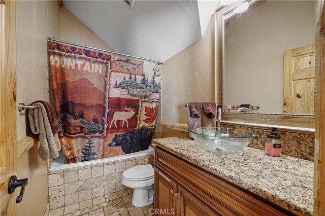 full bathroom featuring toilet, shower / tub combo, vanity, and vaulted ceiling