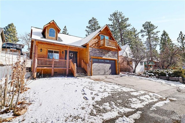 log cabin featuring a porch, a balcony, and a garage