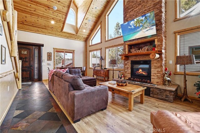 living room featuring a high ceiling, a fireplace, a wealth of natural light, and wood ceiling