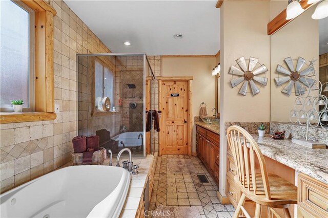 bathroom with tile walls, plus walk in shower, a healthy amount of sunlight, and vanity