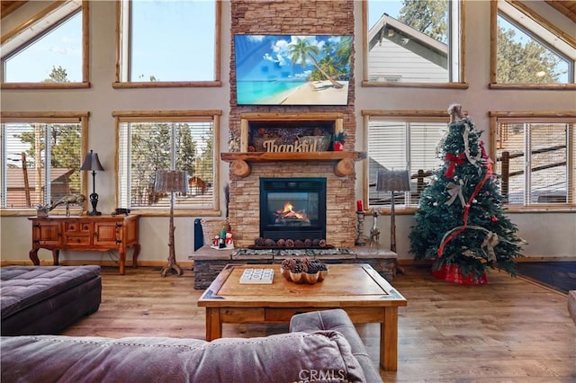 interior space featuring a towering ceiling, hardwood / wood-style flooring, and a stone fireplace