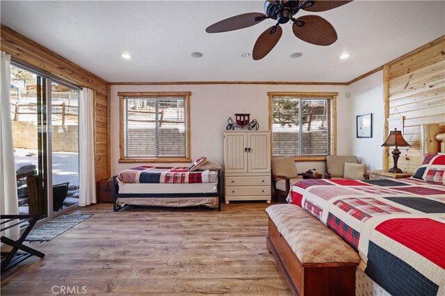 bedroom with light wood-type flooring, ceiling fan, ornamental molding, wooden walls, and access to exterior