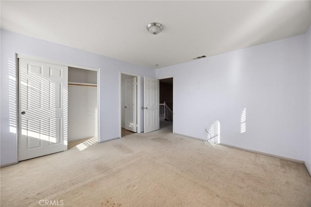 unfurnished bedroom featuring a closet and light colored carpet