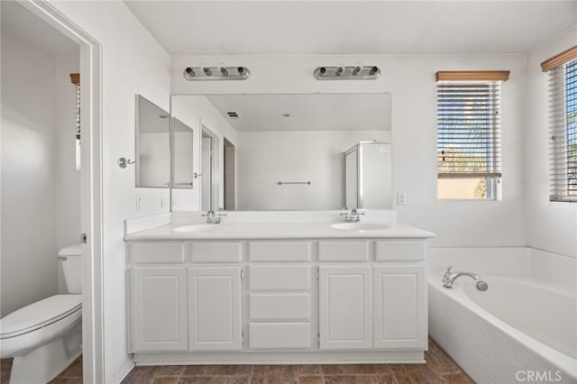 bathroom with a relaxing tiled tub, vanity, and toilet