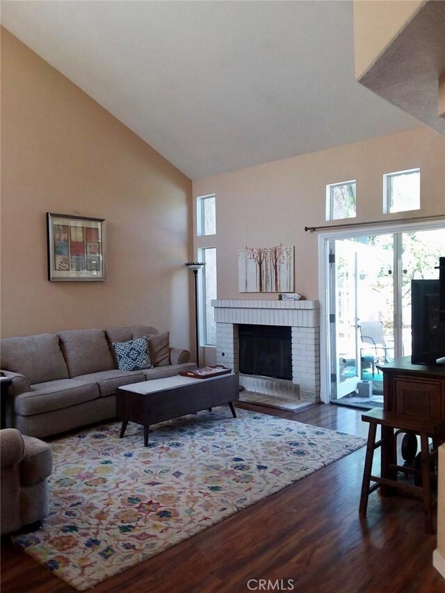 living room with dark wood-type flooring, a fireplace, and high vaulted ceiling