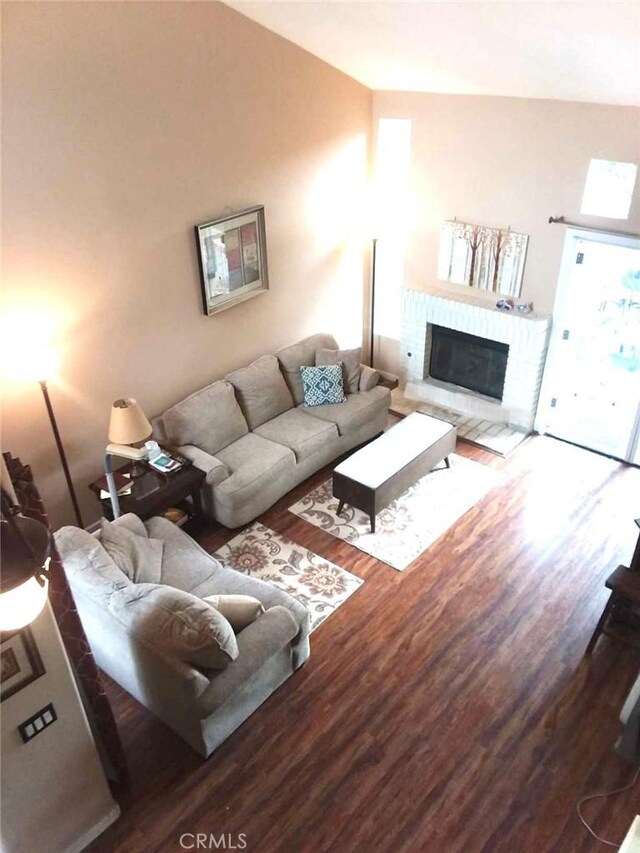 living room with lofted ceiling, wood-type flooring, and a fireplace