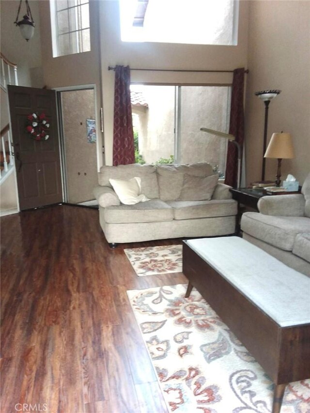 living room featuring a high ceiling, plenty of natural light, and dark hardwood / wood-style flooring