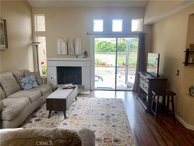 living room with a brick fireplace and dark hardwood / wood-style floors