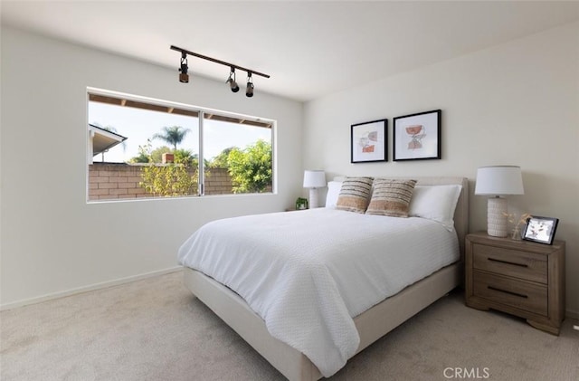 carpeted bedroom with baseboards and track lighting