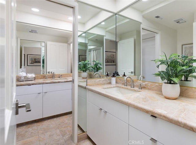 bathroom with visible vents, two vanities, and a sink